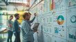 © Naret - Diverse team of professionals collaboratively brainstorming over a project in a modern, plant-filled office space..
