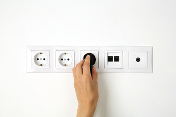 Wall Mural - Woman putting plug into socket indoors, closeup