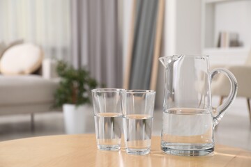 Poster - Jug and glasses with clear water on table indoors, closeup. Space for text