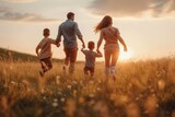 Fototapeta Natura - A happy family holds hands and runs through a field during sunset, symbolizing love, togetherness, and healthy lifestyle