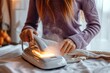 An attractive woman in a purple sweater using a high-tech steam iron with light indicators for ironing a shirt