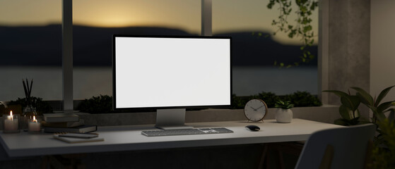 A modern home office in the evening with a PC computer mockup on a table against the window.