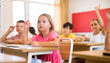 © JackF - Portrait of positive pupil girl raising hand to answer during lesson at classroom