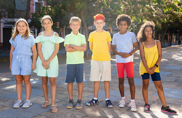 Group of positive interracial children standing together outdoors during sunny day. Smiling kids on summer vacation.