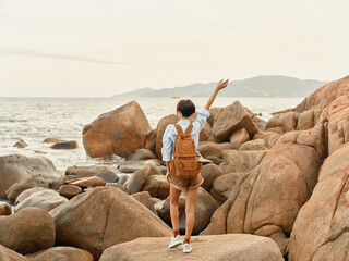 Sticker - Tropical Sunset Adventure: A Happy Woman Walking on a Beach with a Backpack, Enjoying a Carefree Trip and Smiling at the Ocean