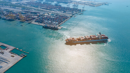 Aerial cargo container ship running to international customs freight sea port. Container ship near cargo harbour shipyard