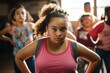 An obese girl, 11 years old, of mixed race, looking shyly at the camera while participating in a dance class with other children.