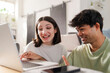 © Studio Marmellata - Young couple sharing a fun moment while shopping online, with the woman pointing at the laptop screen and smiling