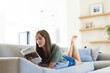 © Wavebreak Media - A young Caucasian woman is relaxing on a couch while reading a magazine, with copy space unaltered