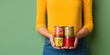 Closeup woman hands holding red metallic package of a canned food on isolated green background with space for copy