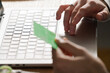 © Studio Marmellata - hand placing a credit card on a laptop trackpad, symbolizing a secure online transaction from home