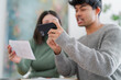 © Studio Marmellata - A young man captures an image of a paper document using his smartphone, with a focused expression as a woman looks on. The scene suggests a moment of sharing information or digitizing paperwork