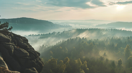 The misty panorama unveils a beautiful sunrise casting its glow upon the rocky mountains, offering a view of the foggy valley below.