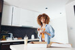 © SHOTPRIME STUDIO - Woman with curly hair enjoying a delicious breakfast with a box of donuts and a cup of coffee in a cozy kitchen