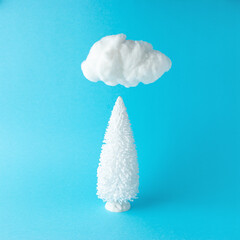 Wall Mural - Snowy Christmas tree under cotton cloud on pastel blue background. Christmas or New Year minimal concept.