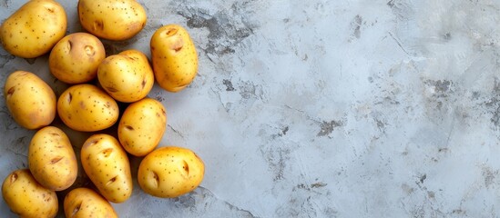 Canvas Print - Potatoes placed on concrete background, seen from above with empty space around.