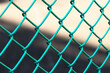 Close-up green metal chain link fence with blurred background