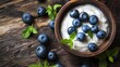 Top view of delicious fresh blueberries with creamy yogurt on a textured background