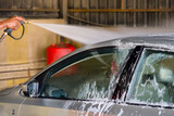 Fototapeta Sawanna - Car wash with high pressure water and foam in a car wash