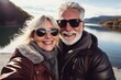 © Evon J - A couple of pensioners in sunglasses take selfies on a smartphone while traveling in the mountains