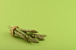 Bunch of fresh asparagus on green paper background. Copy space