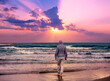 Seascape in the evening with a beautiful sky. A man walks barefoot on the beach and looks at a magical sunset