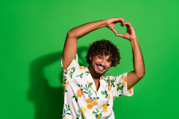 Wall Mural - Photo of funky cheerful arabian man wear print shirt rising arms showing heart gesture empty space isolated green color background