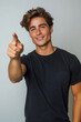 Young man on white background pointing ahead with a smile. Jeune homme sur fond blanc montrant du doigt devant lui avec le sourire.