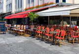 Fototapeta Paryż - Typical view of the Parisian street with tables with tables of cafe in Paris, France. Architecture and landmark of Paris. Cozy Paris cityscape