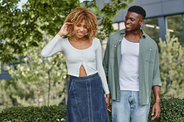 happy african american couple holding hands and walking together outdoors, woman in braces