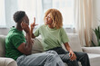 African American couple communicating using a sign language on couch, black man in hearing aid