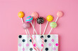 a bag with colored lollipops and candies on a pink ba