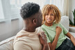 © LIGHTFIELD STUDIOS - Black couple using sign language for communication at home, happy woman in braces looking at man