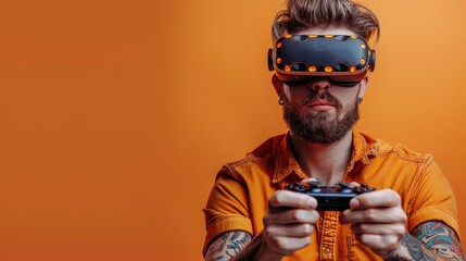 Wall Mural - A tattoed young brunet man in his early 20s wears apricot shirt and holds a VR headset as he plays a video game with joystick console on a pastel orange background.