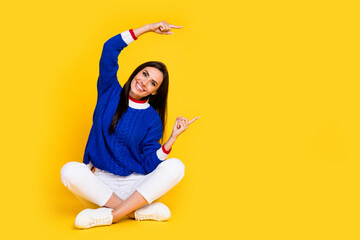 Sticker - Full body photo of beautiful brunette woman dressed blue knitwear point fingers billboard in your city isolated on yellow color background