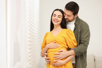 Sticker - Happy pregnant woman with her husband indoors, space for text