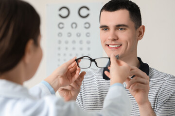 Canvas Print - Vision testing. Ophthalmologist giving glasses to young man indoors