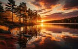 Fototapeta Zachód słońca - A beautiful sunset casting warm orange hues over a calm lake surrounded by trees and rocks.