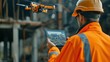A construction engineer in high visibility gear operates a drone using a tablet at a construction site for surveillance and inspection.