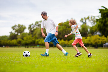 Father and son play football. Dad and kid run.