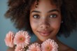 Portrait of happy smiling african american dark skinned woman with curly hair, with pink flowers, on blue background, Banner, poster, wallpaper
