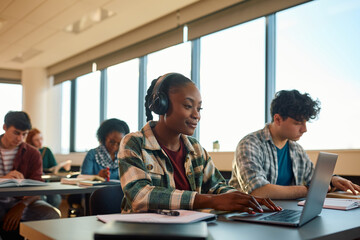 Wall Mural - Smiling black female student e-learning on laptop at university campus.