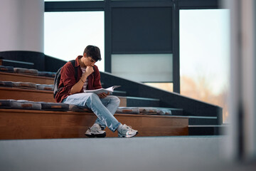 Wall Mural - Young male student learning in lecture hall at university.