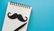 black paper mustache on a notepad with a felt tip pen month donations concept for the study and control of prostate cancer and other male diseases mock up flat lay copy space