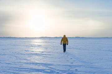 Wall Mural - Lonely man in yellow down jacket walk the ice of frozen sea