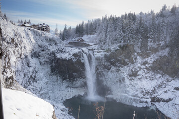 Canvas Print - a waterfall in the snow near many trees and rocks with people taking pictures