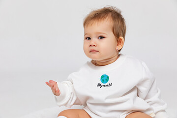 Portrait of a happy little newborn baby girl in a white bodysuit with inscription my world on white background, save the planet. Earth day concept with copy space