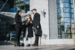 © qunica.com - Three young entrepreneurs engage in a serious business discussion outside a modern city building, with paperwork and ideas in hand.