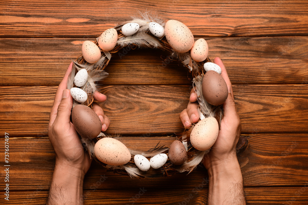 Man holding Easter wreath on brown wooden table