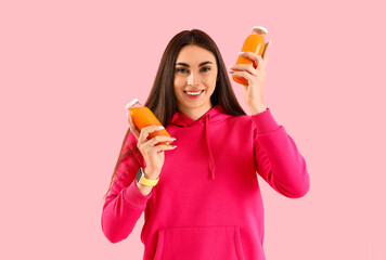 Poster - Young woman with bottles of juice on pink background